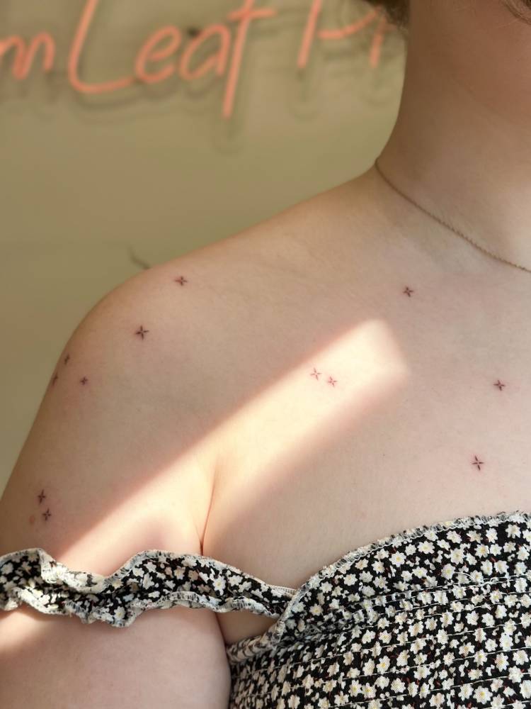 Sparkling stars tattoo located on the shoulder, minimalistic style.