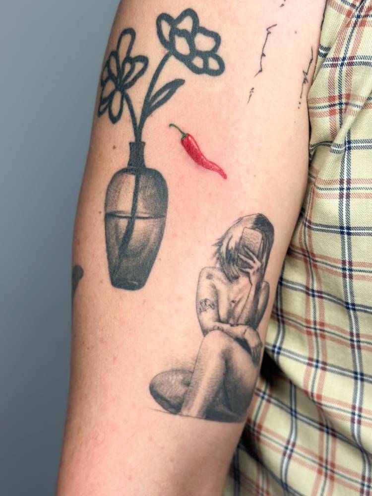 Red chili pepper tattoo in illustrative style located on the upper arm.