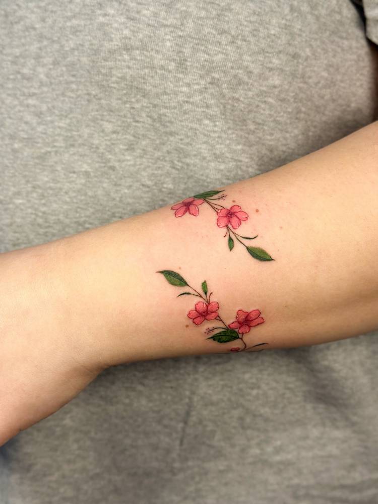 Cherry blossom flower bracelet tattoo located on the wrist.