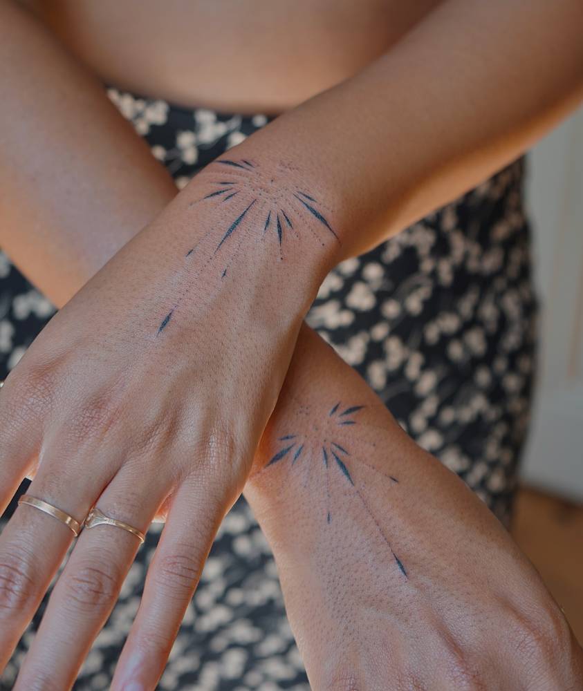 Matching ornaments tattoo hand poked on the wrists.