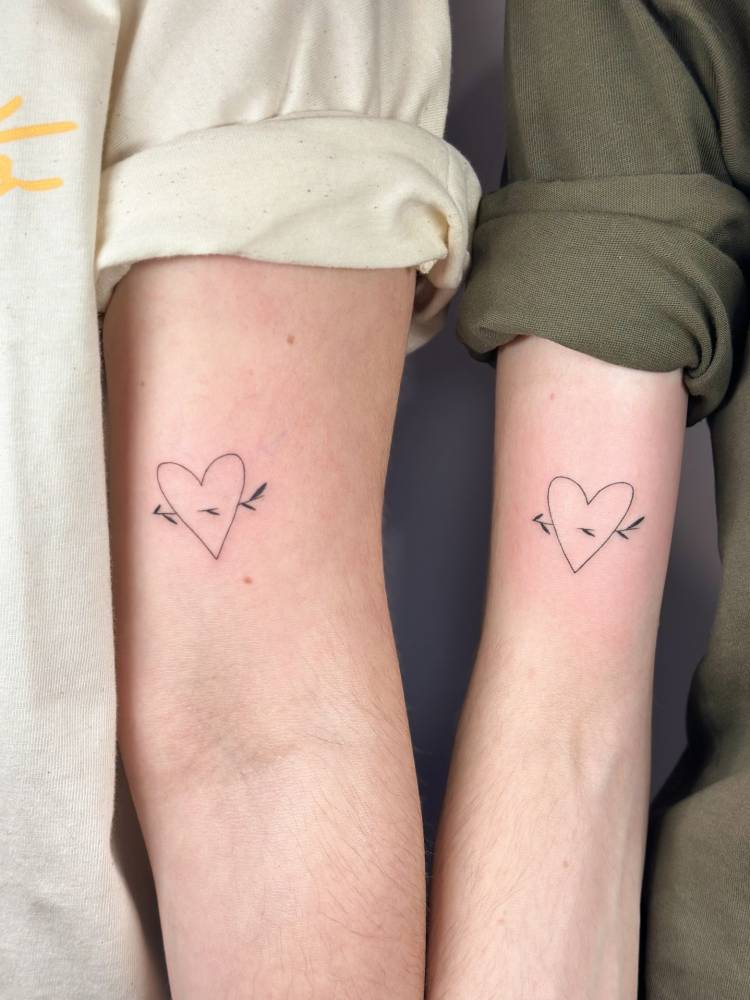 Matching heart and arrow tattoo for couple, minimalistic style.