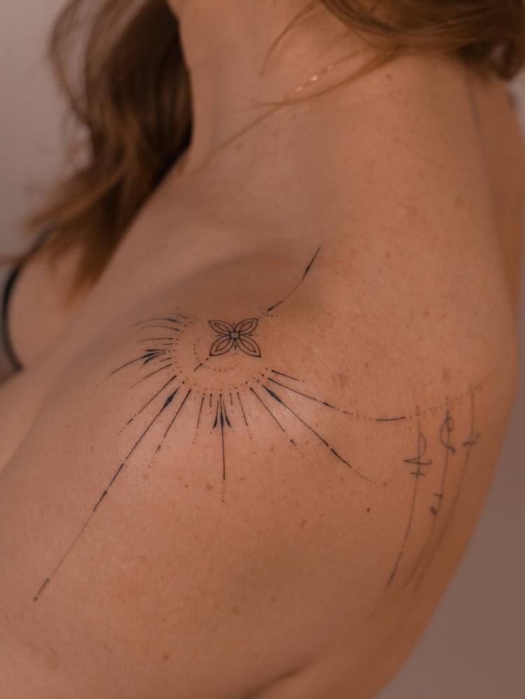 Ornamental design in hand poked style tattooed on the shoulder.