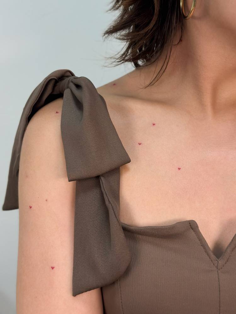 Red heart freckles tattooed on the upper arm and chest.