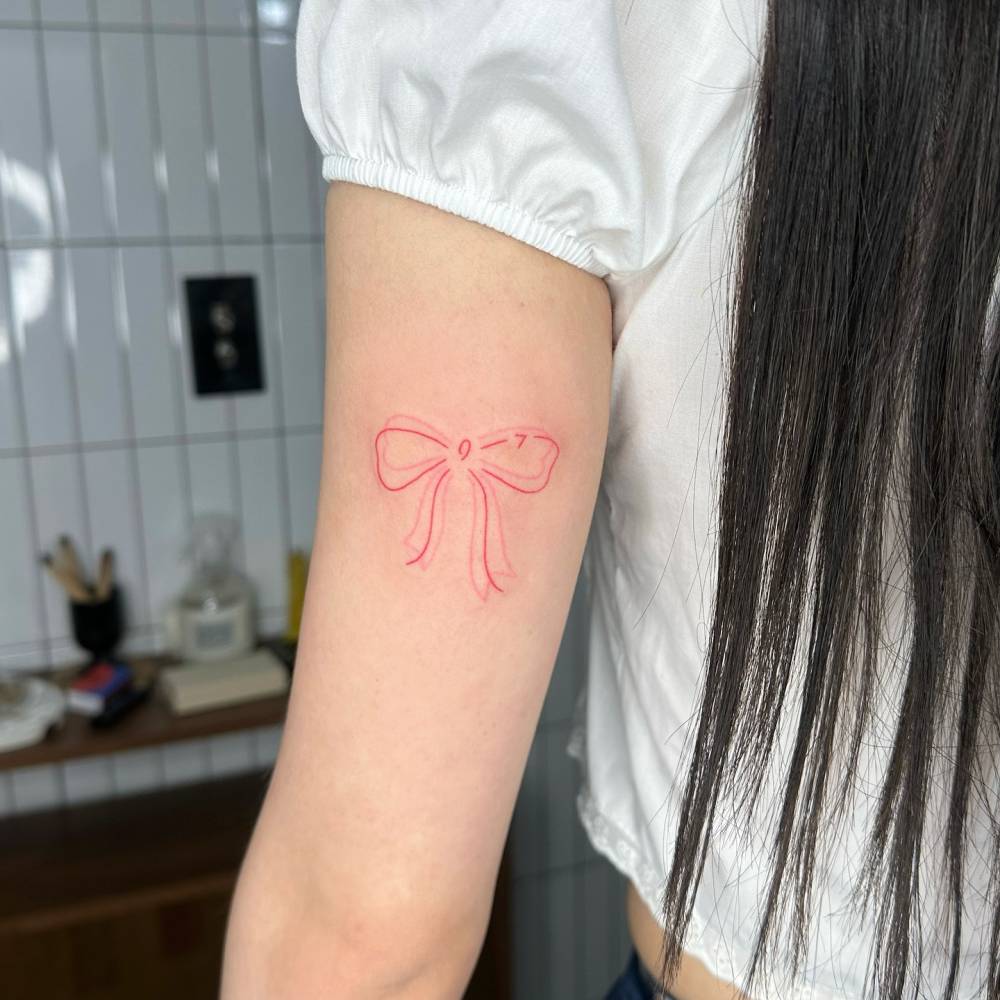 Hand poked bow tattoo located on the tricep.