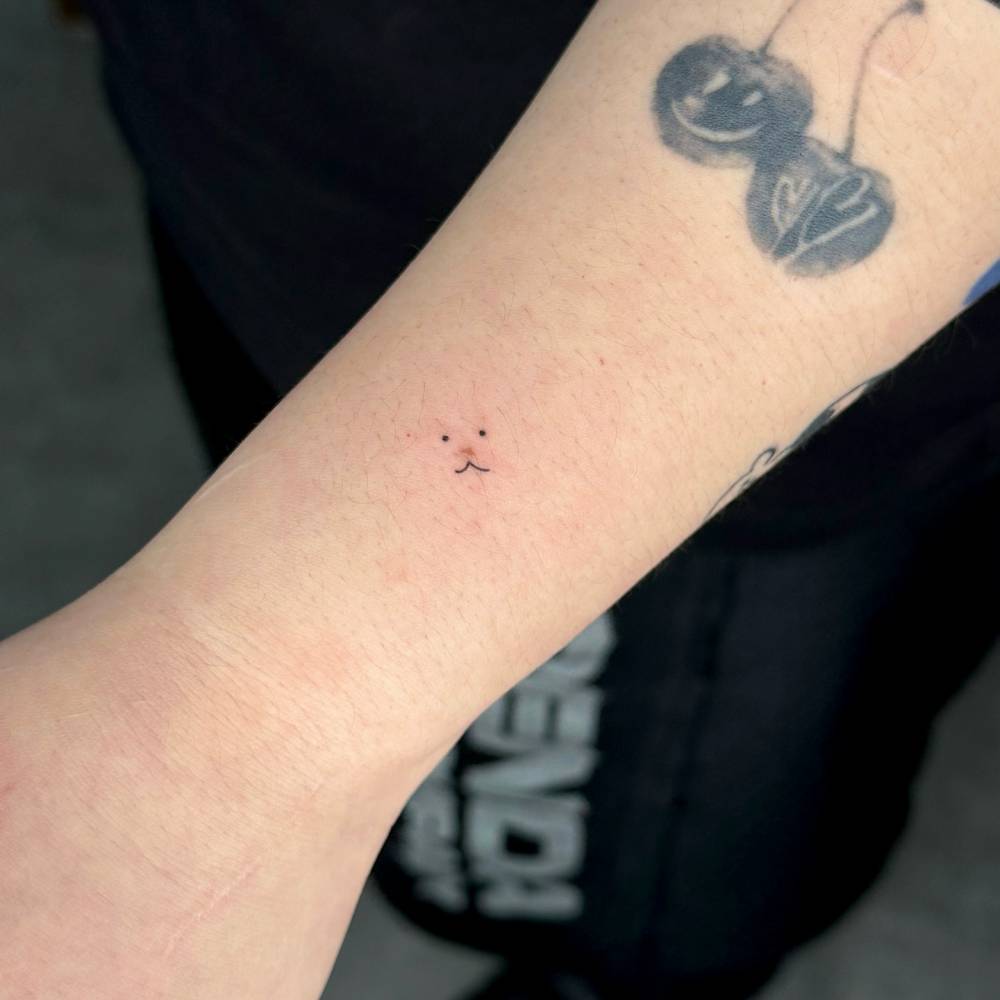 Tiny bear face birthmark cover up tattoo located on the wrist.
