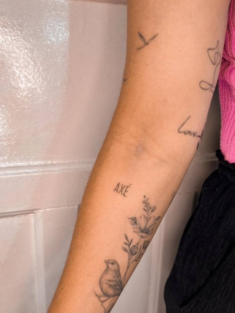 "Axé" lettering tattoo located on the inner forearm.