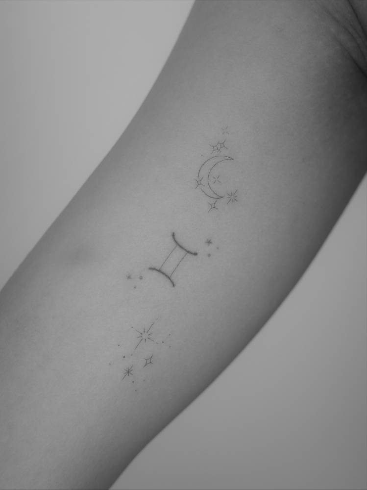 Gemini Zodia symbol, crescent moon and stars tattoo located on the inner arm.