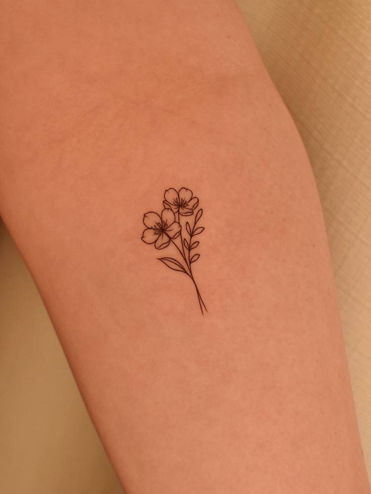 Fine line style little flowers tattooed on the inner forearm.