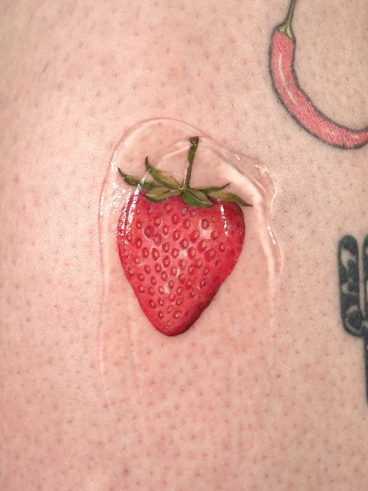 Micro-realistic style strawberry tattoo located on the shin.