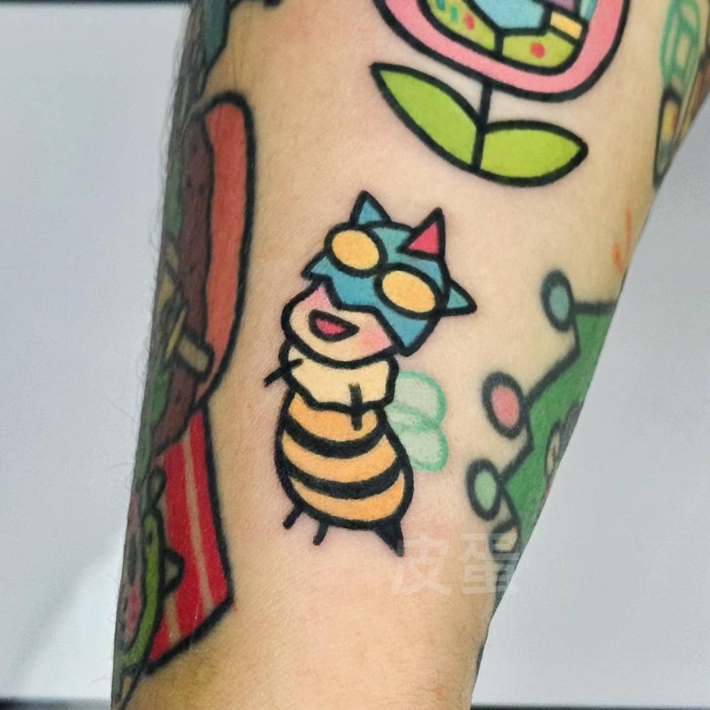 Cartoon style bee tattoo placed on the wrist.