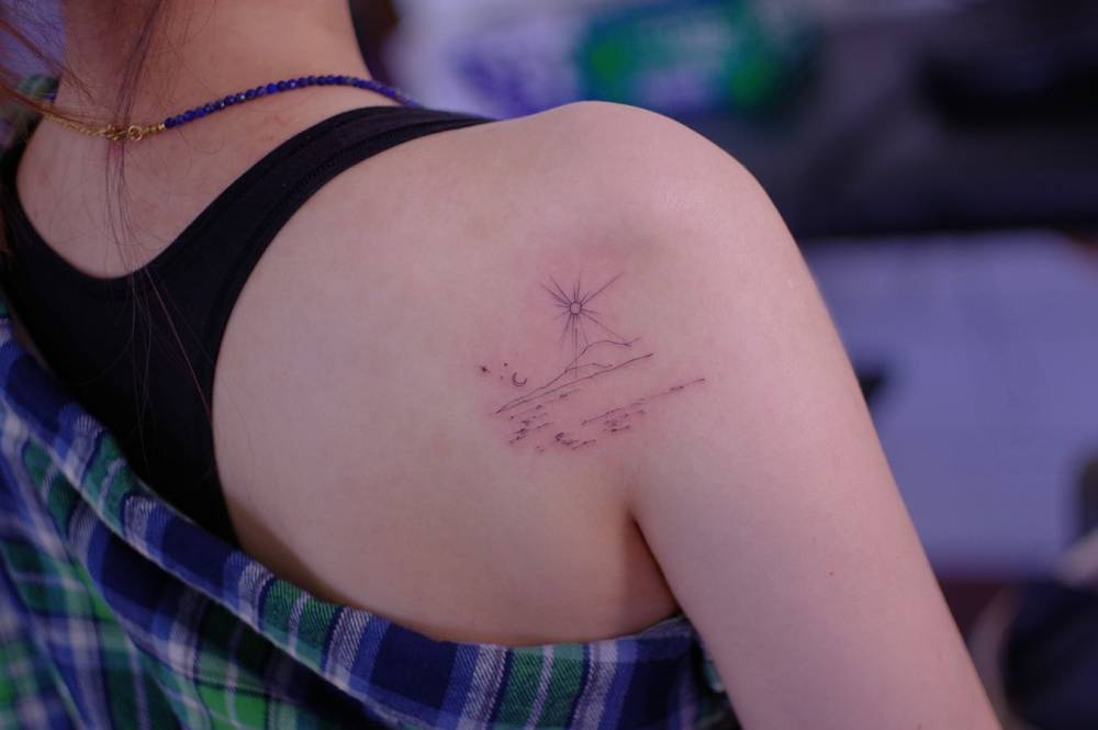 Sea landscape tattoo located on the shoulder blade, fine line style.