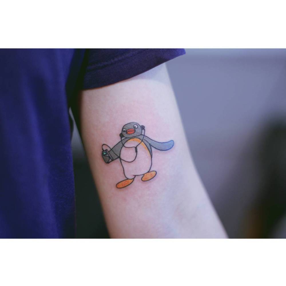 Cartoon style Pingu tattoo located on the inner arm.