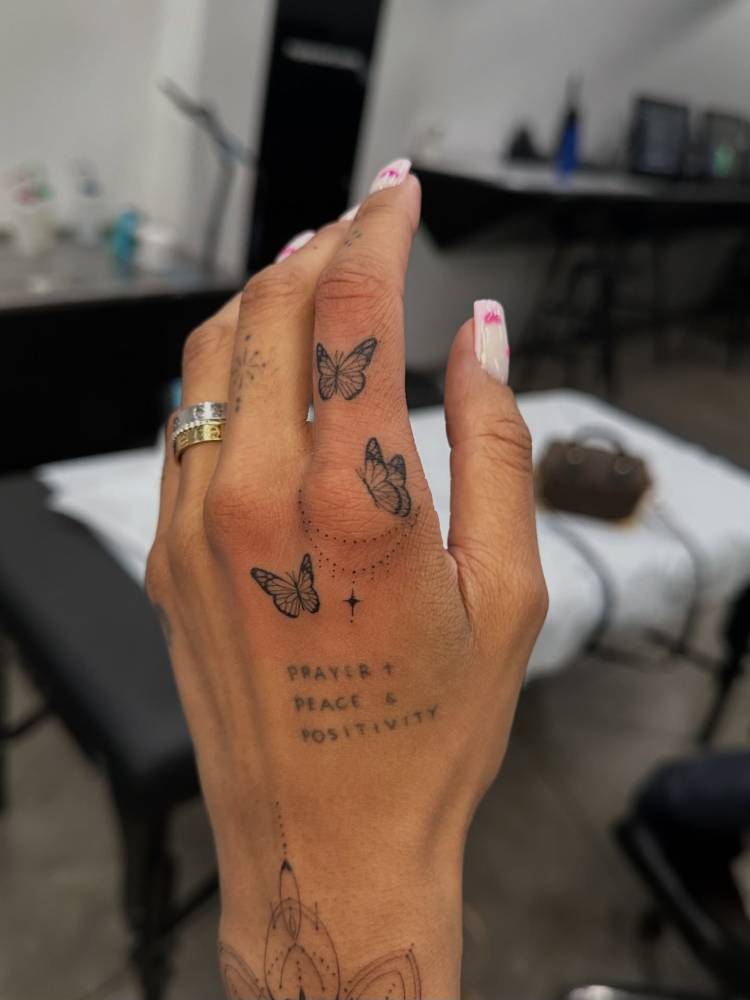 Little butterflies in illustrative style tattooed on the hand.