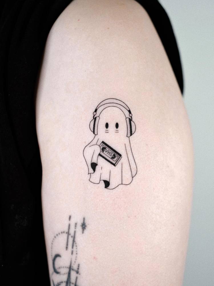 Cartoon style ghost tattoo located on the upper arm.