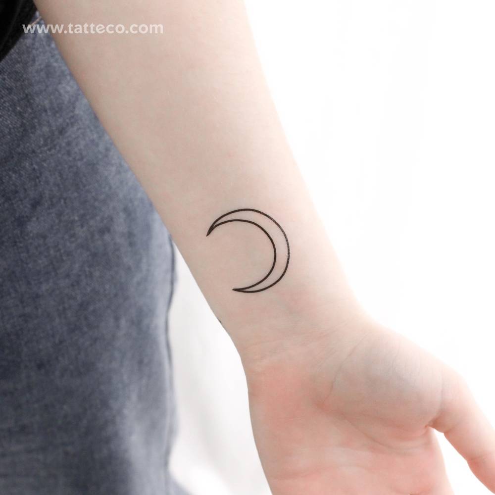 Fine line crescent moon temporary tattoo placed on the wrist.