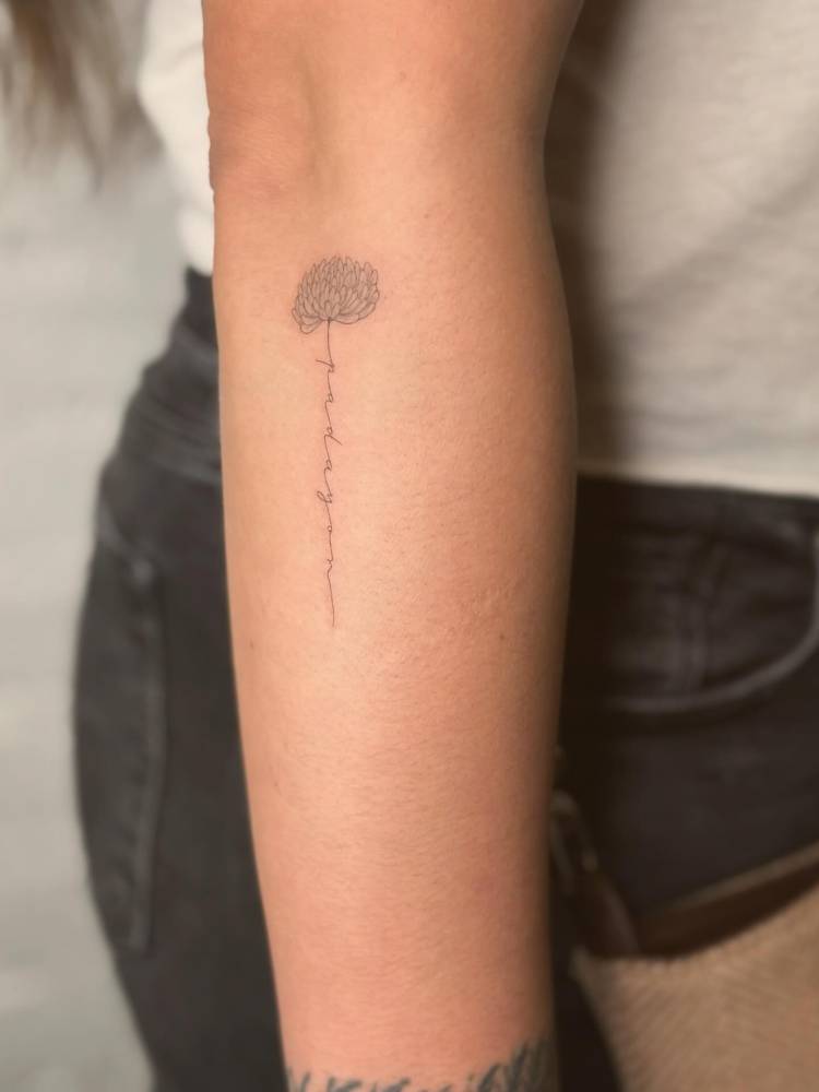 Chrysanthemum and word "padayon" tattooed on the forearm.