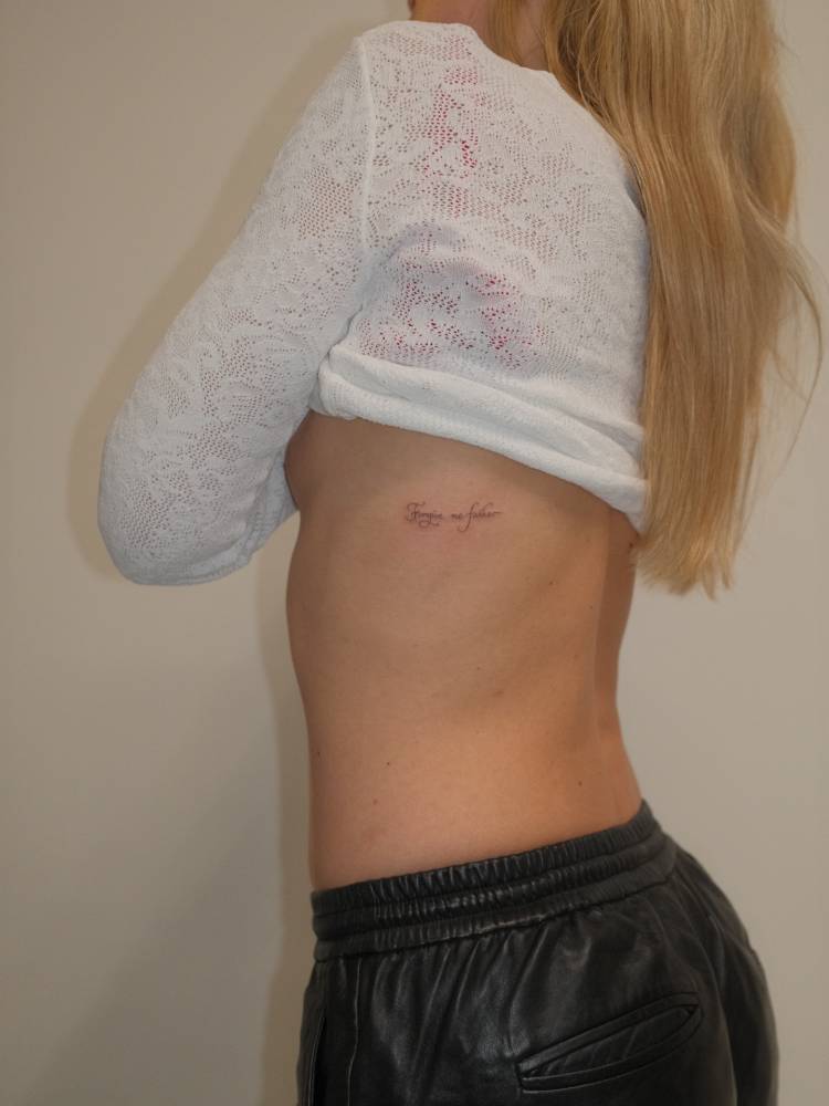 "Forgive me father" lettering tattoo located on the rib.