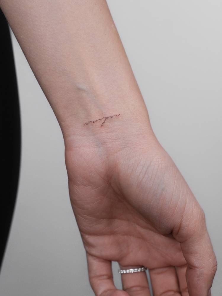 Handwritten font name "Nedine" tattooed on the wrist.