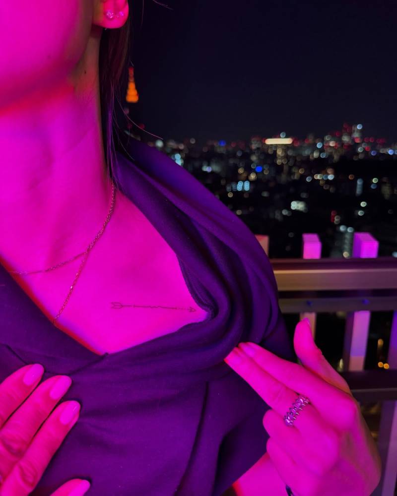 Fine line style arrow tattoo located on the collarbone.