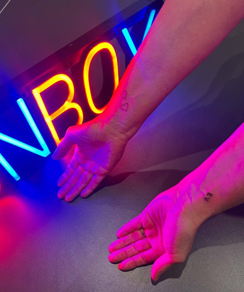Minimalistic hearts and initial tattoos located on the wrists.