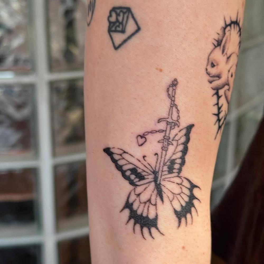 Butterfly and sword tattoo located on the forearm.