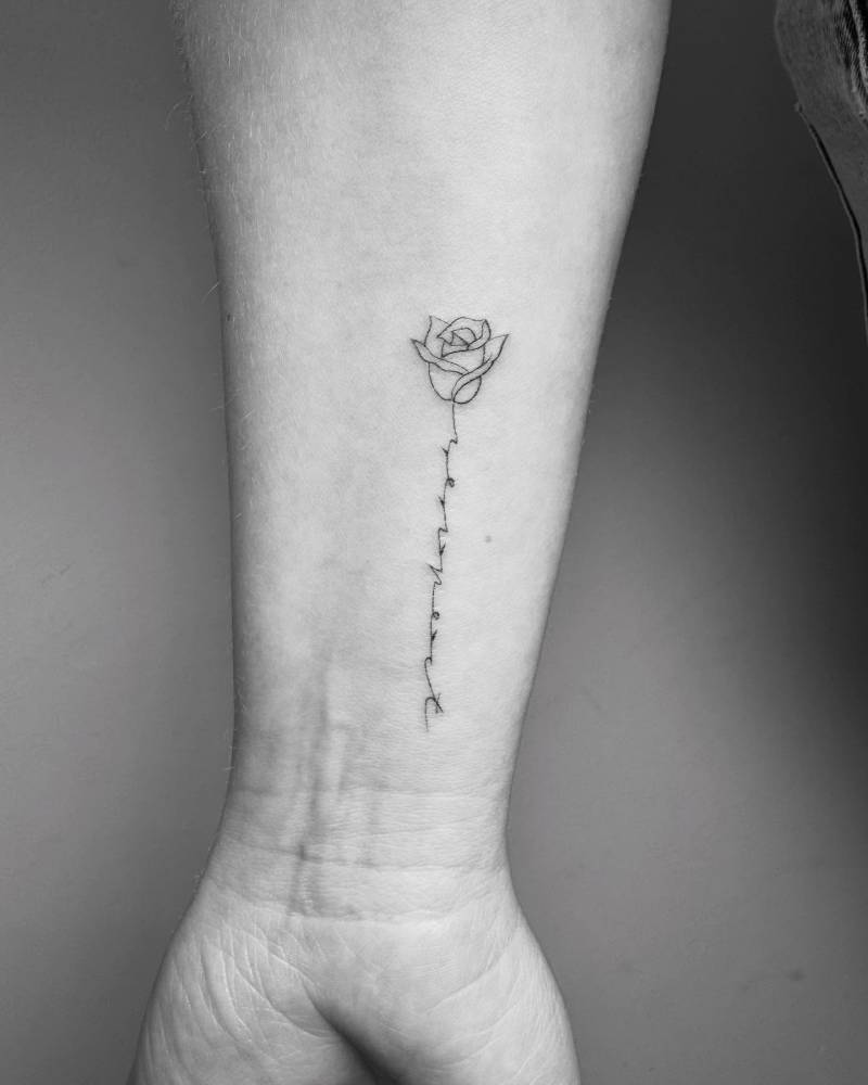 Rose and scrip lettering tattooed on the wrist.