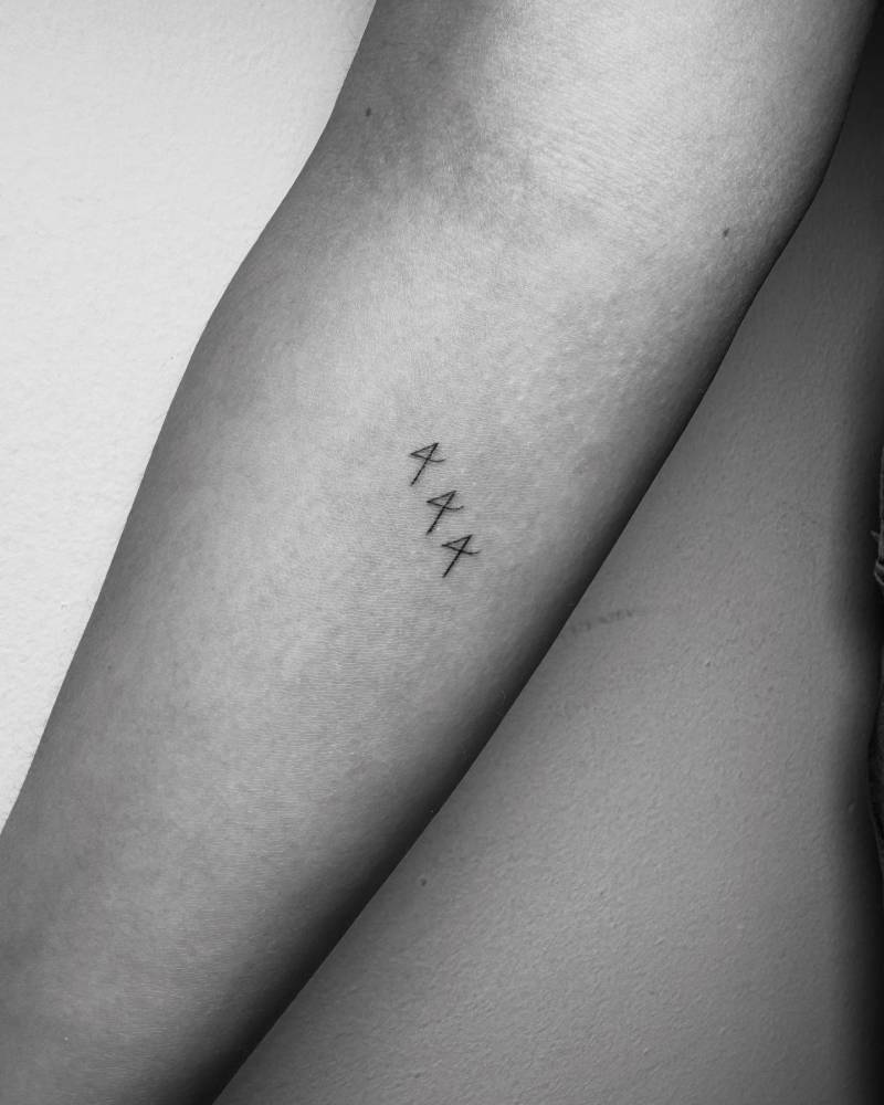 Angel number "444" tattoo located on the inner forearm.