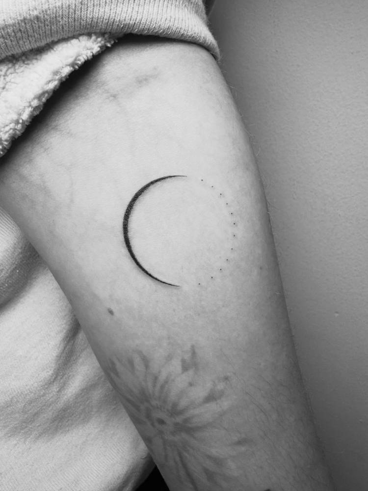 Crescent moon tattoo in minimalistic style located on the inner forearm.