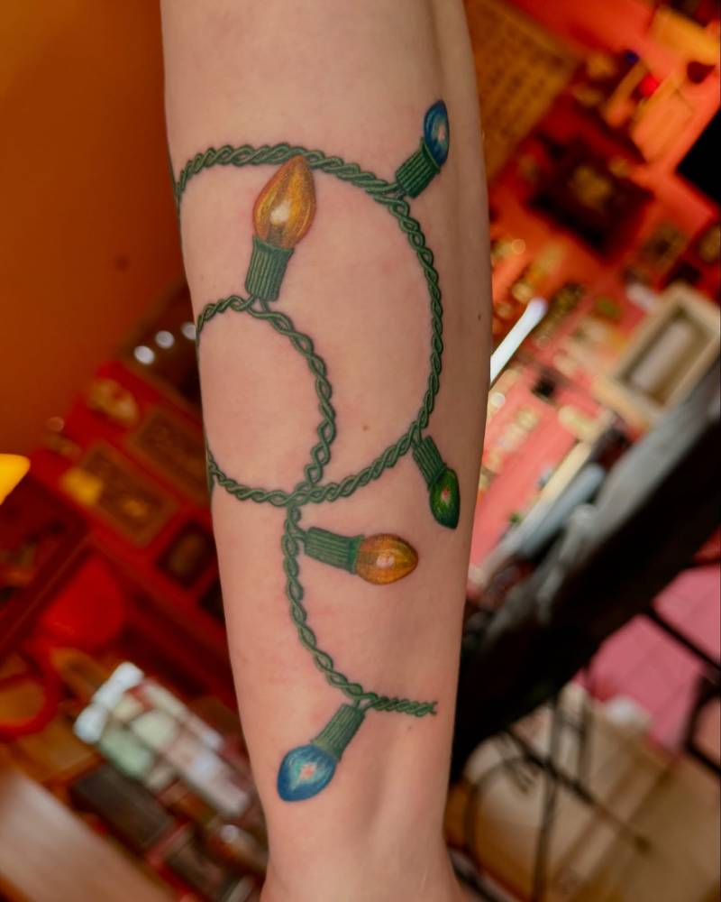 Christmas Lights tattoo located on the inner forearm.