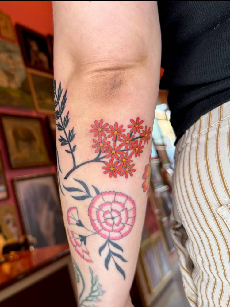 Little flowers tattooed on the forearm, illustrative style.