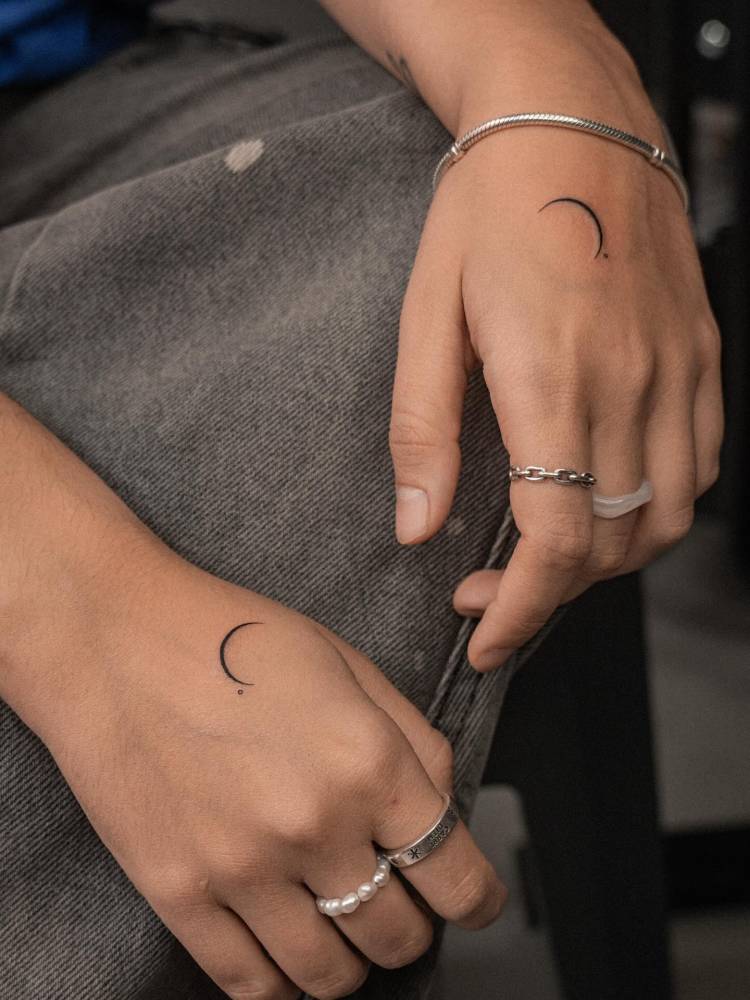 Individual matching minimalistic crescent moon tattoos.