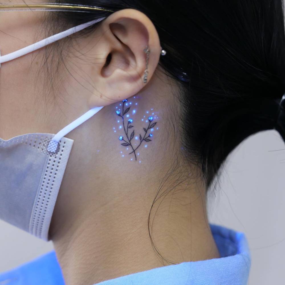 UV ink baby's breath tattoo located behind the ear.