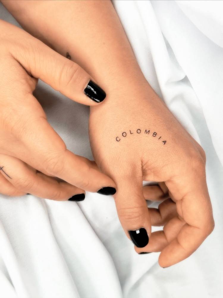 "Colombia" lettering tattoo located on the hand.