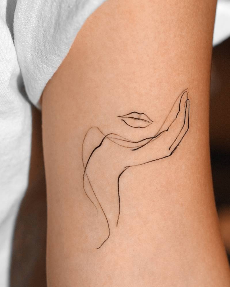 Minimalistic woman portrait tattoo located on the bicep.