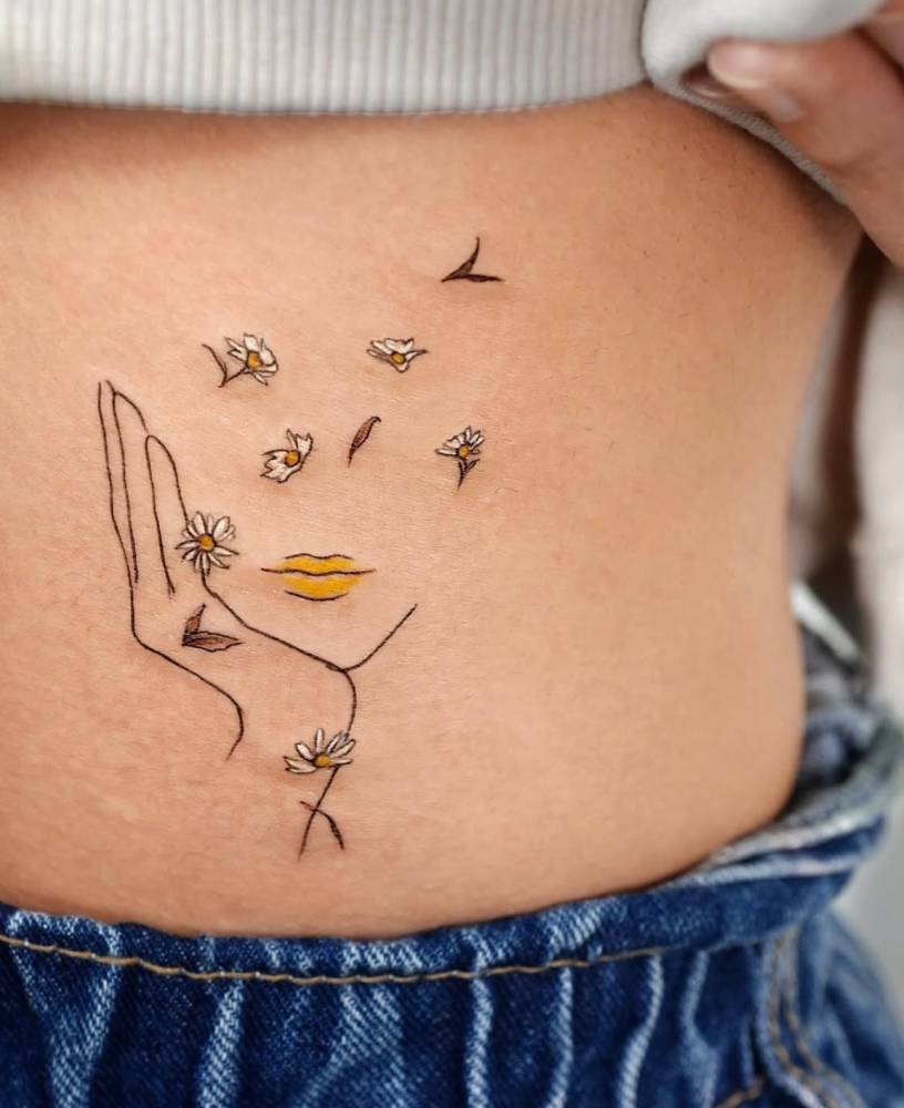 Flower head woman tattoo in sketch work style located on the lower back.