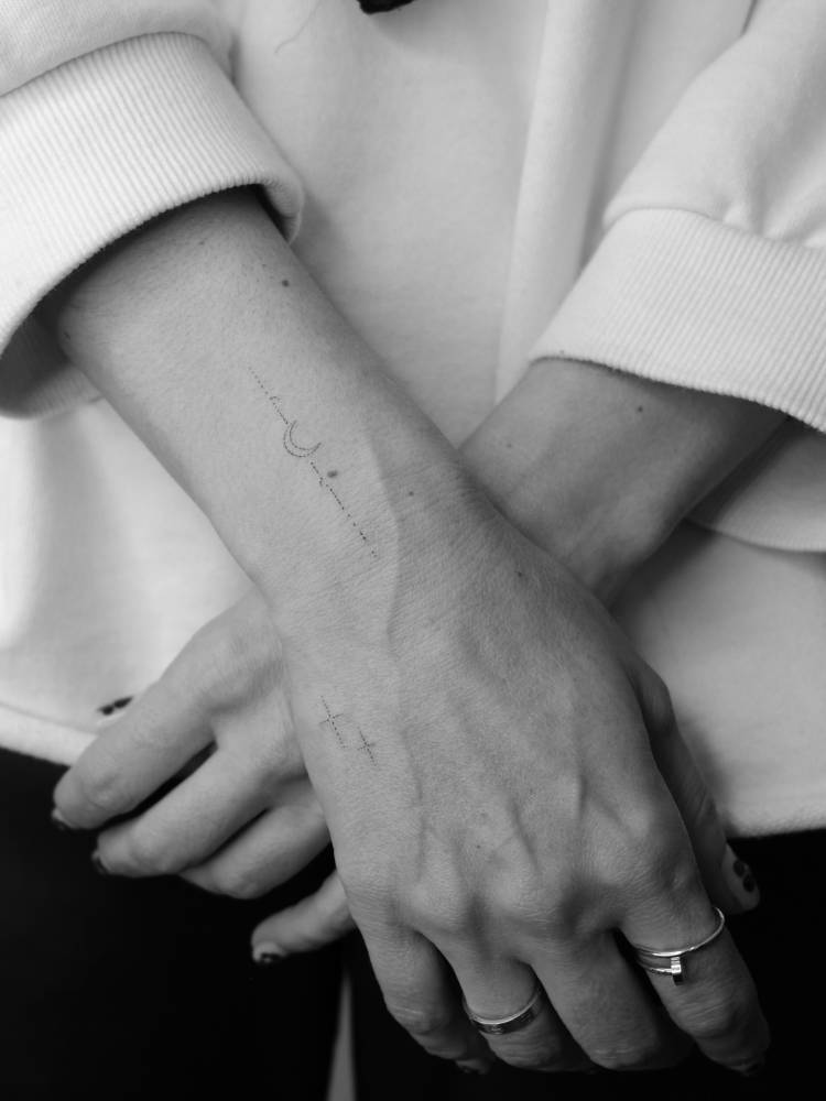Fine line style crescent moon tattoo located on the wrist.