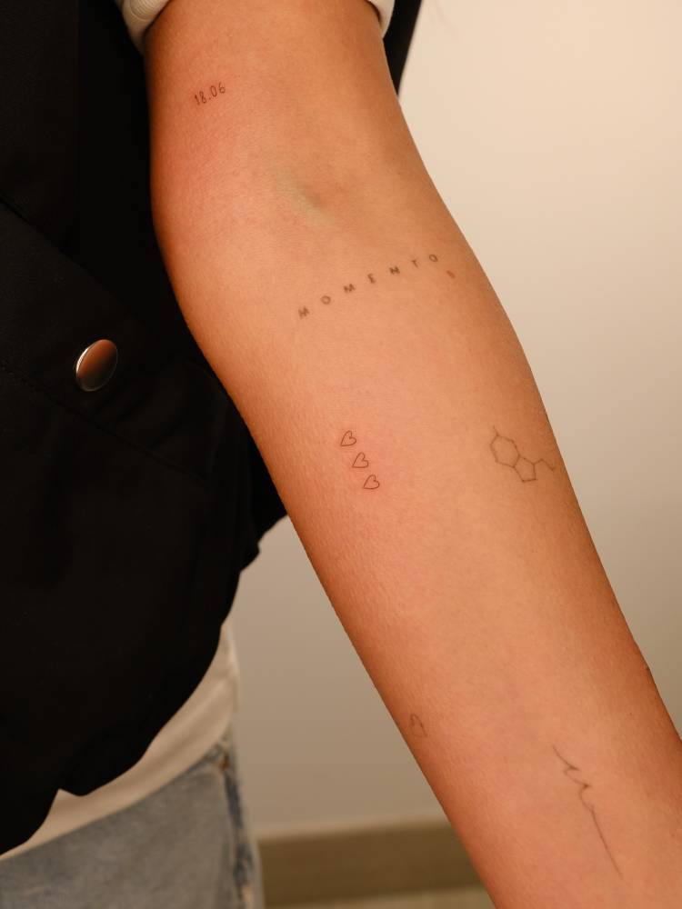Three little hearts tattoo in minimalistic style located on the inner forearm.