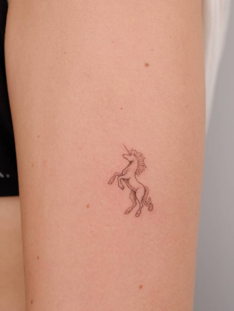 Unicorn tattoo in fine line style located on the thigh.
