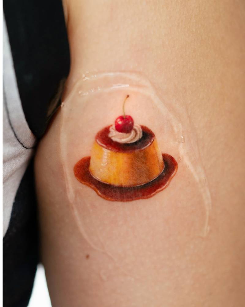 Micro-realistic style pudding tattoo placed on the upper arm.