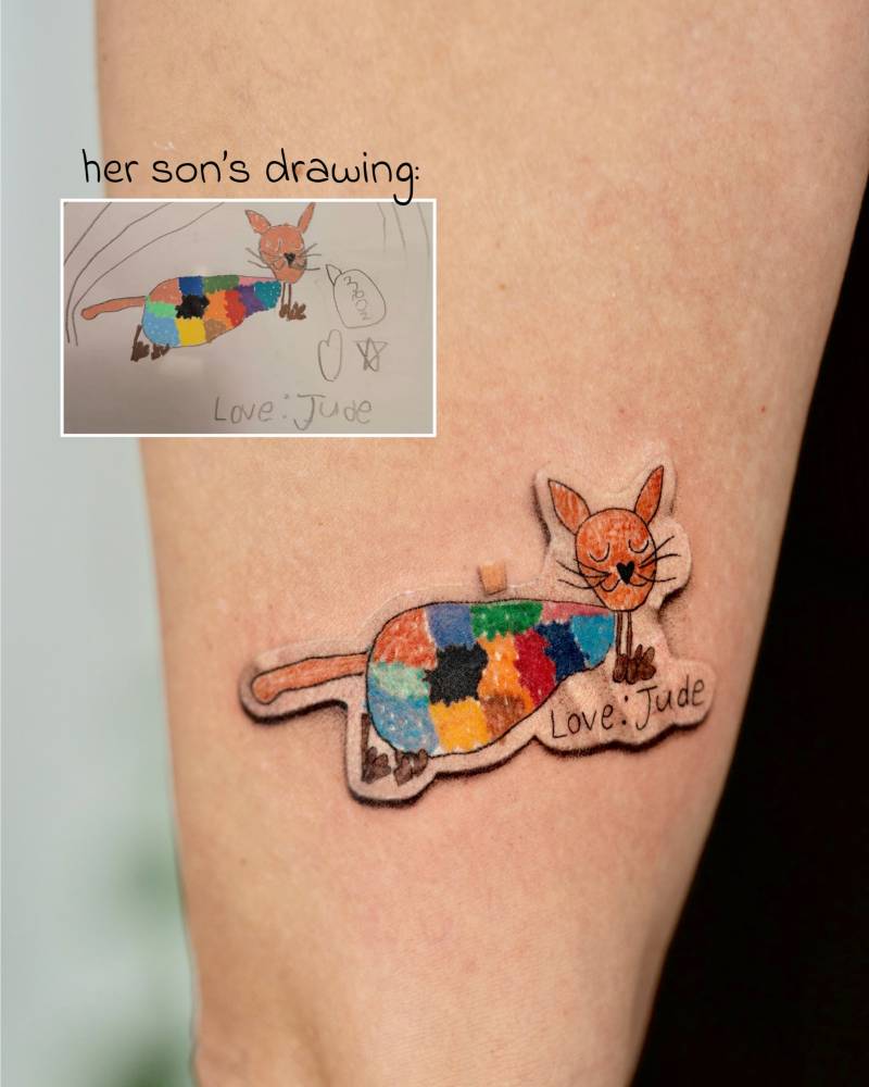 Her son's drawing as a sticker tattooed on the upper arm.