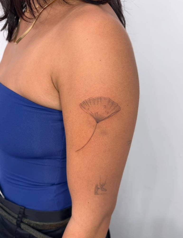 Ginkgo leaf tattoo done on the upper arm, illustrative style.
