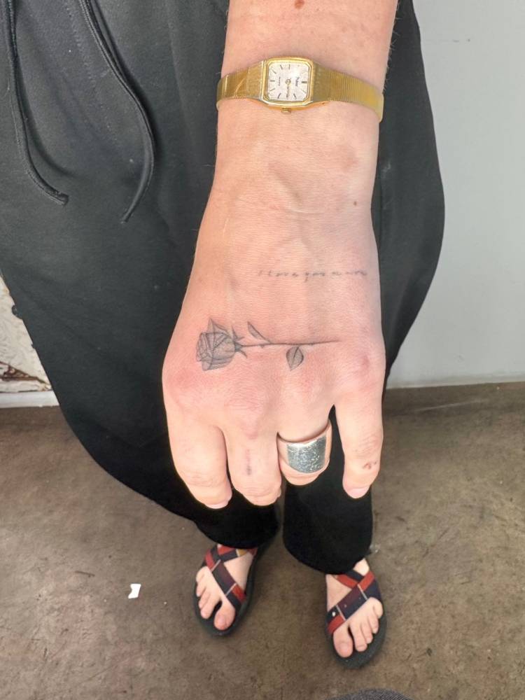 Healed rose tattoo in illustrative style done on the hand.
