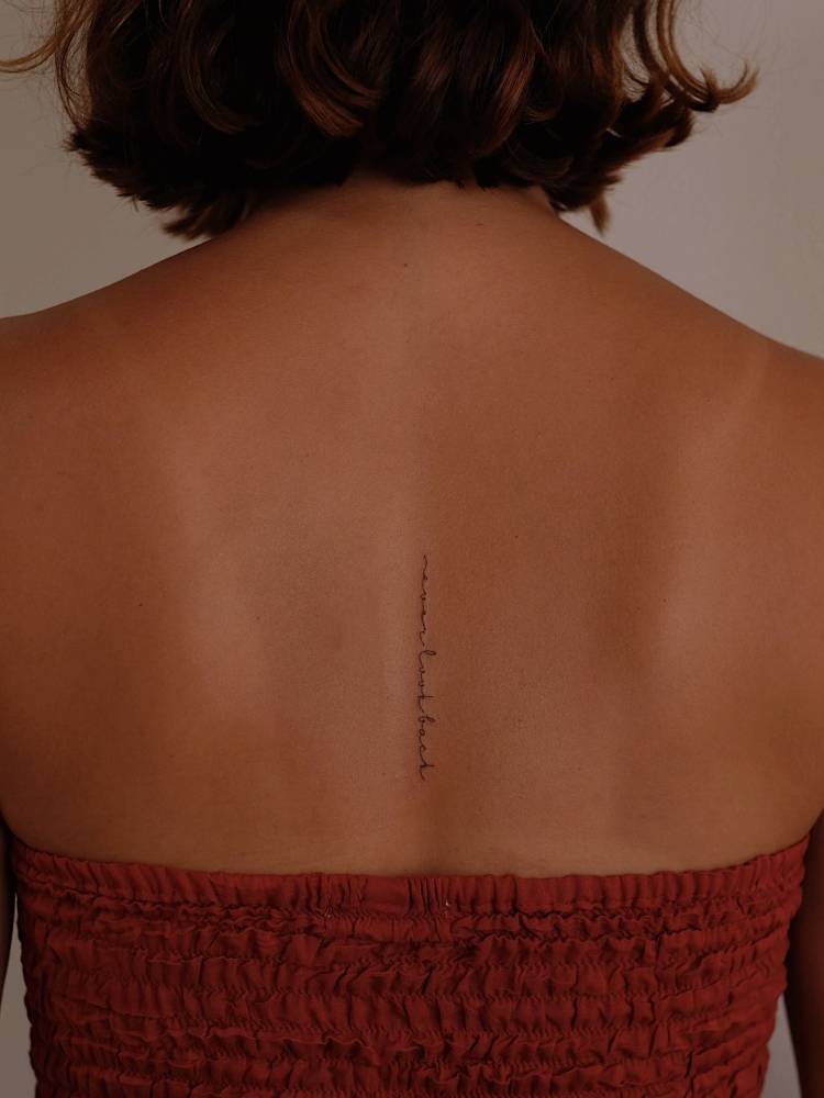 “Never look back” in handwritten font tattooed on the back.
