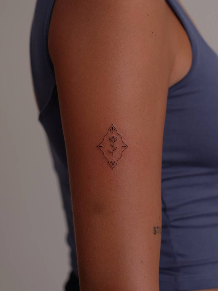Ornamental flower tattoo located on the upper arm.