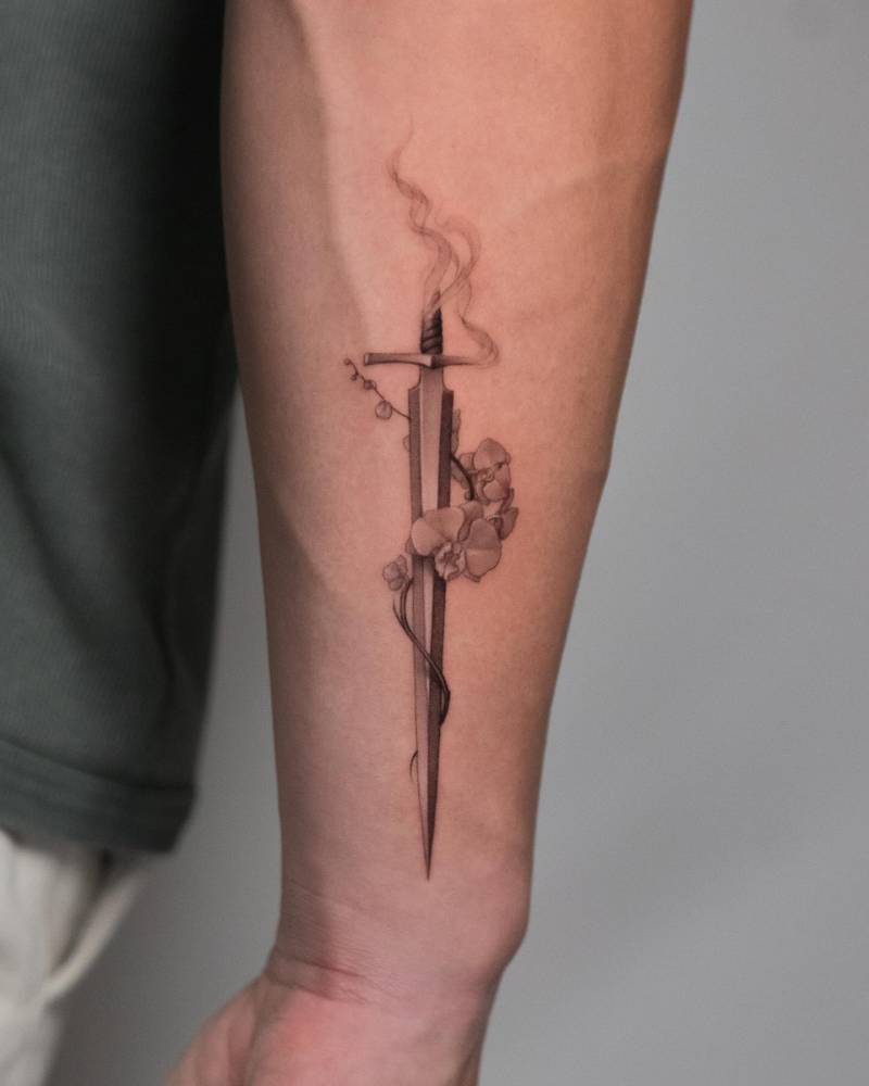 Micro-realistic style sword and orchids tattoo located on the forearm.