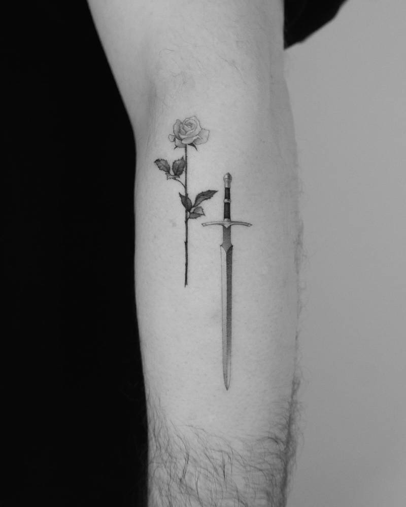 Sword and rose tattoo in micro-realism located on the forearm.