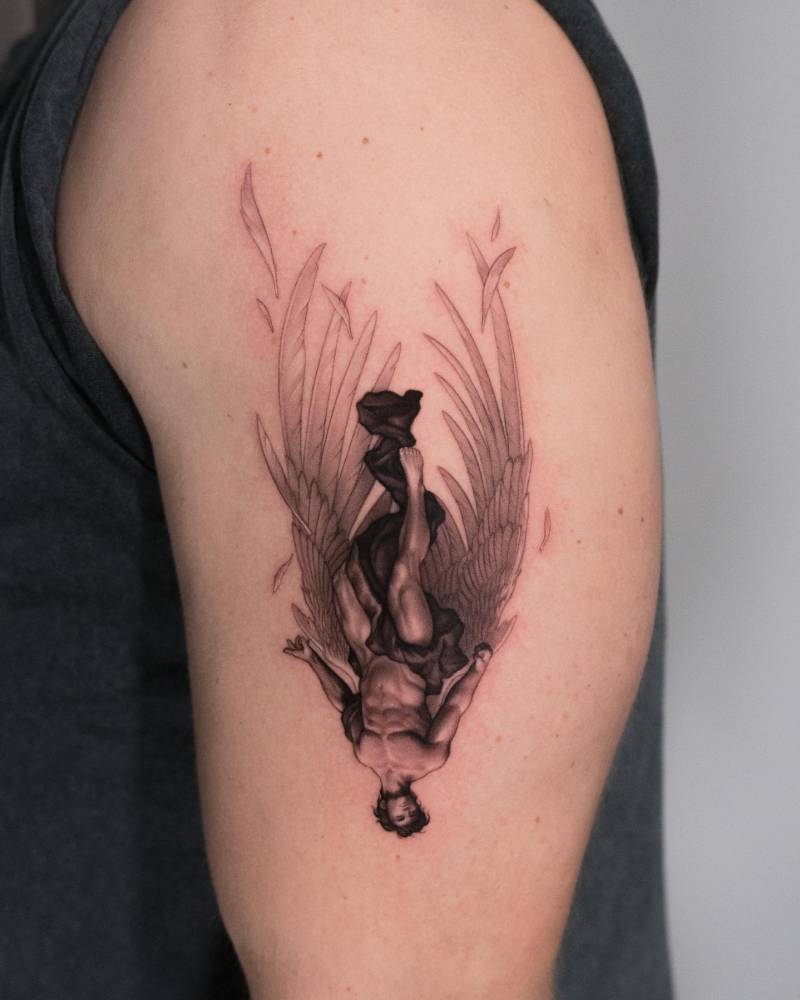 Upside down Icarus tattoo located on the upper arm, classical style.