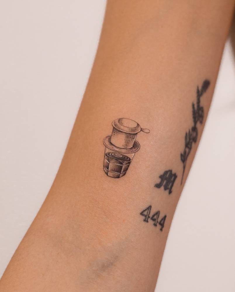 Vietnamese coffee tattooed on the bicep, illustrative style.
