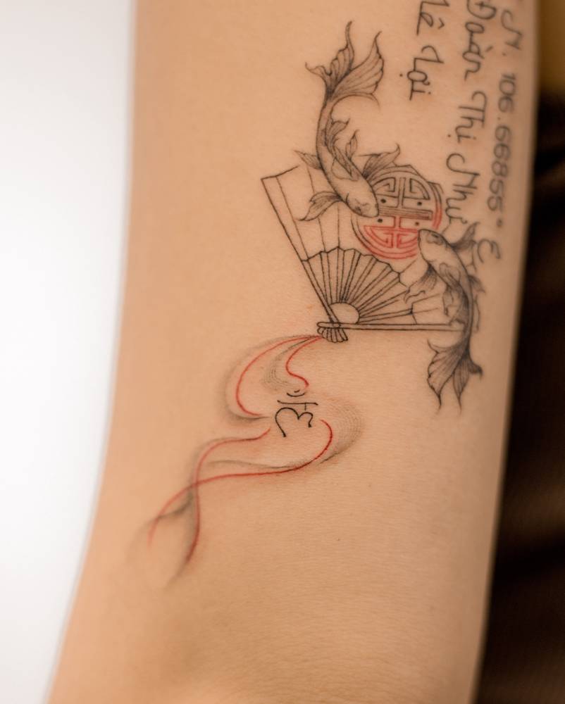 Two opposite fish and hand fan tattoo located on the tricep.