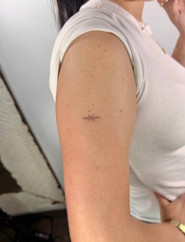 Single needle barbed wire tattoo done on the upper arm.